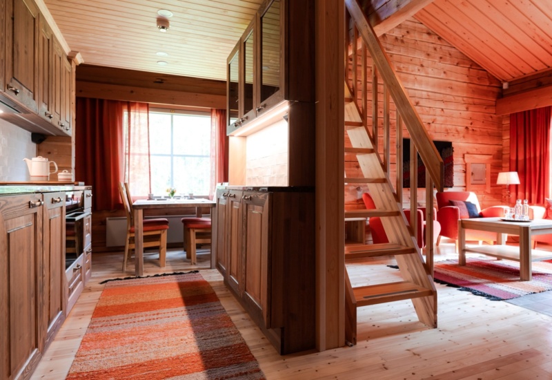 Wooden staircase dividing a timber lodge into the kitchen and living areas.
