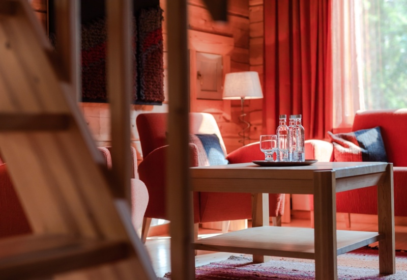 A living room with a small coffee table, red curtains in the background and a red sofa & couch.