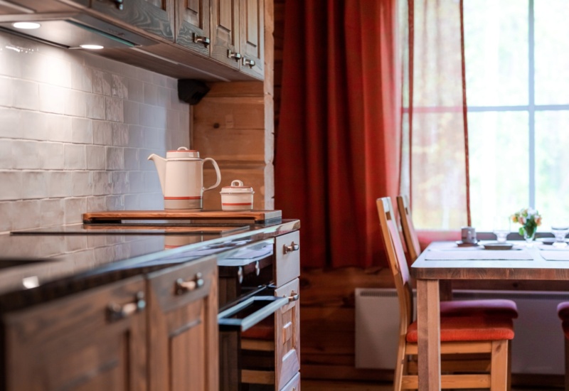 A cozy kitchen, with wooden furniture and red cushions.