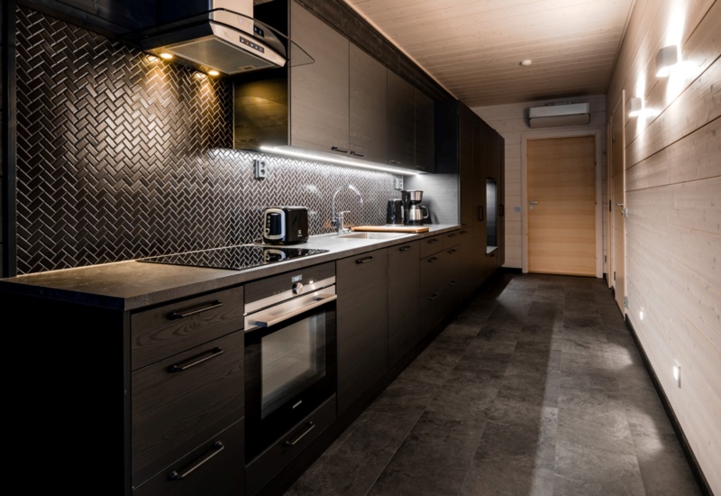 A lodge kitchen, decorated with black stone tiles and black furniture.