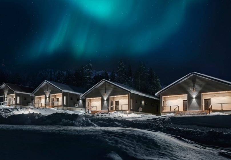 4 houses at night, with the darkness illuminated by their lights and the northern lights in the sky.
