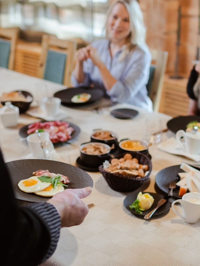 Multiple gourmet dishes on the table served to 2 smiling guests.