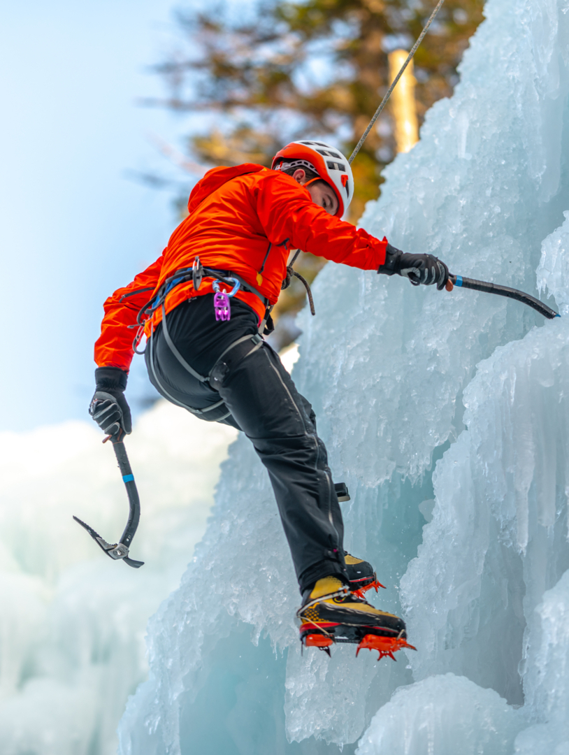A women ice climbing using specialized equipment.