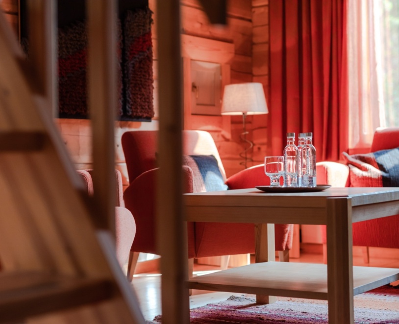 A living room with a small coffee table, red curtains in the background and a red sofa & couch.