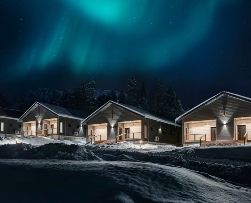 4 houses at night, with the darkness illuminated by their lights and the northern lights in the sky.