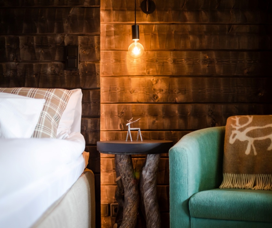 A timber bedroom illuminated by a single light bulb casting warm light on the furniture.
