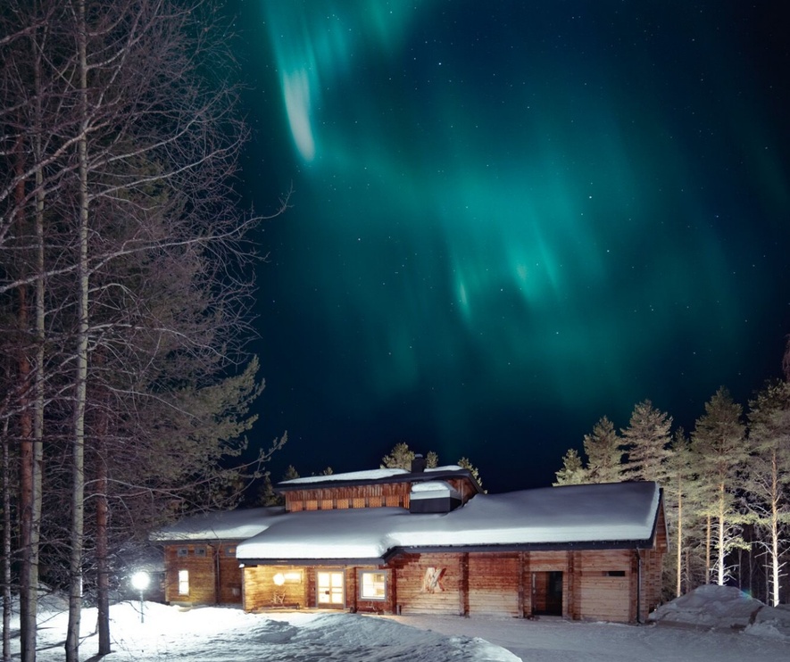 Northern lights descending upon the wooden lodge of the Sunday Morning Resort.
