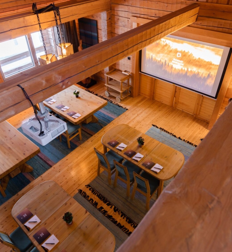 A timber conference room, with a projector attached to a beam and a screen on the wall.