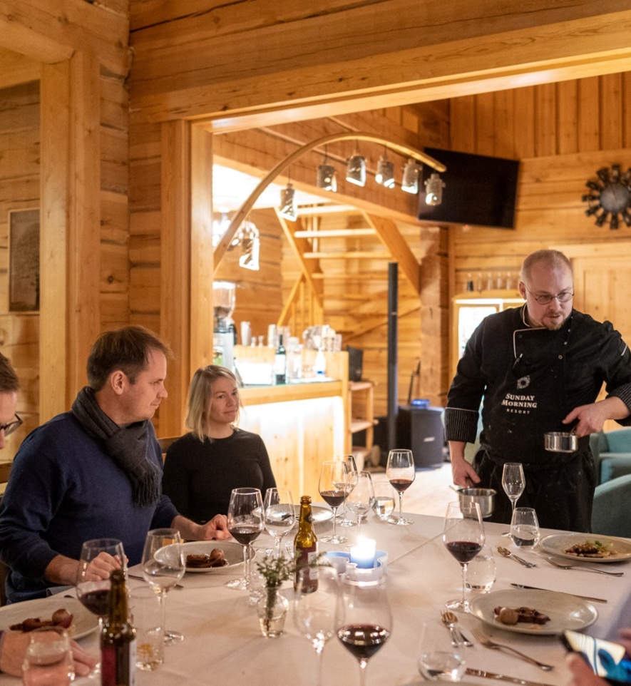 Apartment guests sitting at their table, while the chef serves traditional nordic cuisine.
