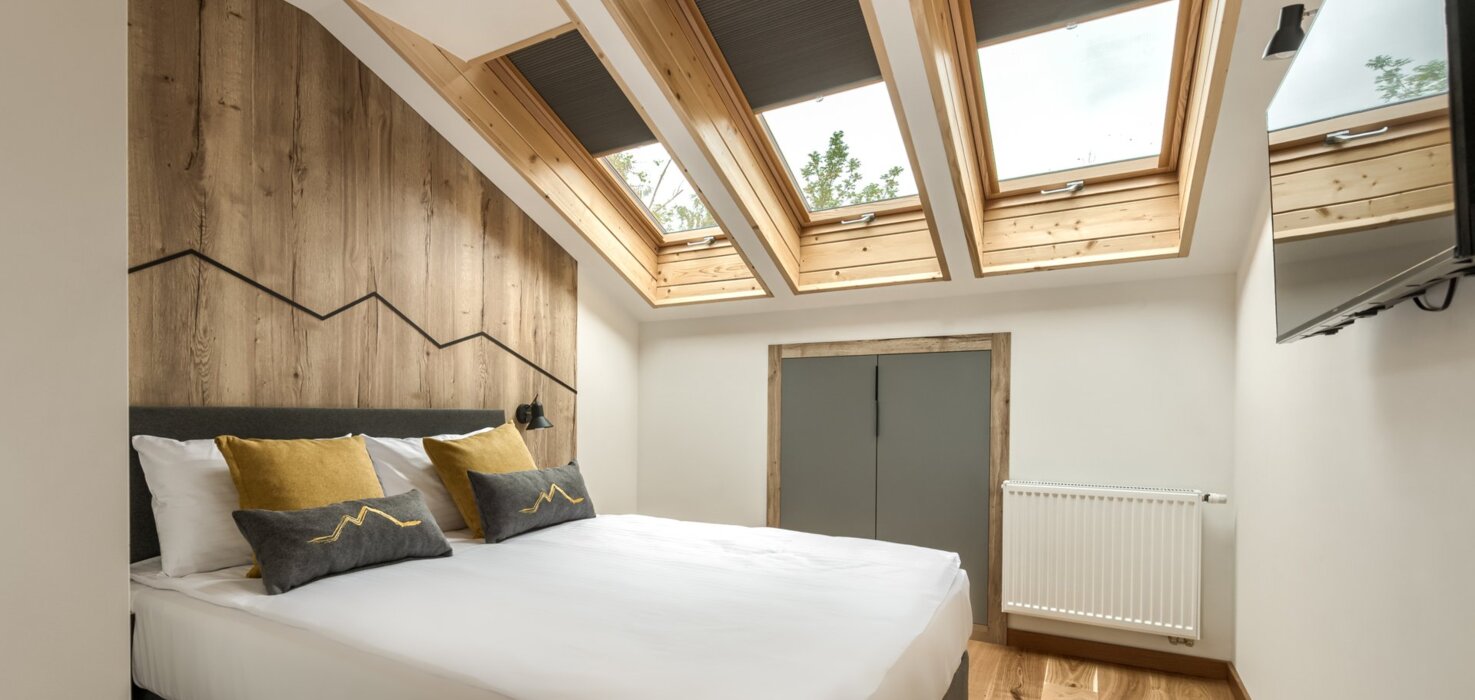 Przytulna sypialnia na poddaszu z widokiem na góry, idealna na nocleg w Zakopanem.