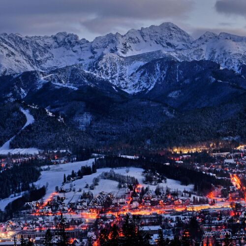 Panoramiczny widok na Zakopane w słoneczny dzień, z wyraźnie widocznymi górami w tle.