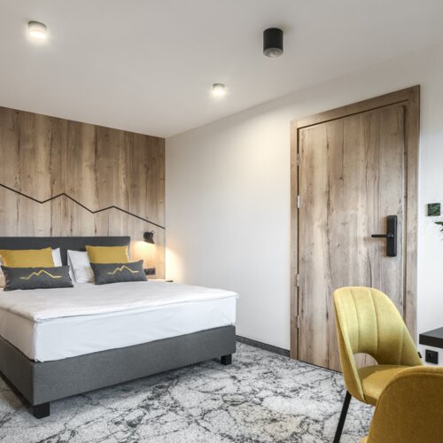 Przytulny pokój dwuosobowy z ciepłymi, drewnianymi wykończeniami, idealny na relaks w Zakopanem.