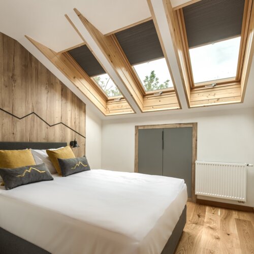 Przytulna sypialnia na poddaszu z widokiem na góry, idealna na nocleg w Zakopanem.