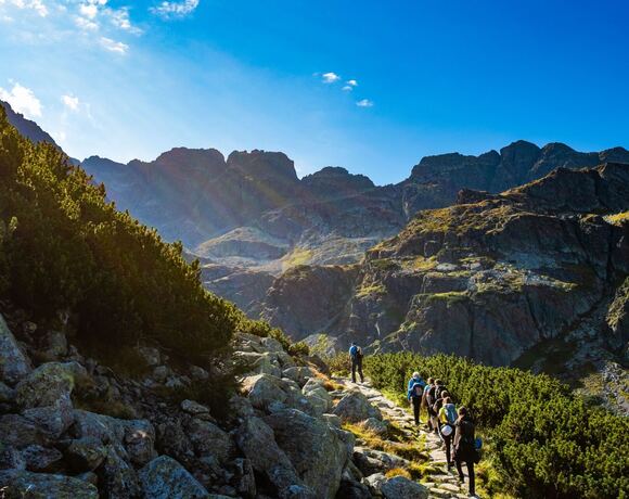 Skupina turistů na horské túře s batohy, v pozadí Tatry