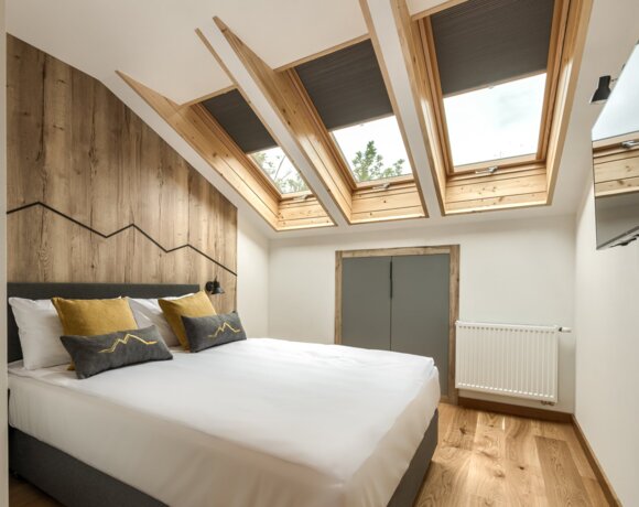 Przytulna sypialnia na poddaszu z widokiem na góry, idealna na nocleg w Zakopanem.