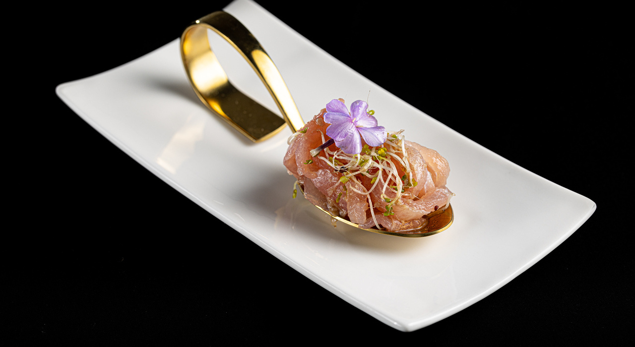 Exquisite salmon dish with edible flower served on a decorative spoon