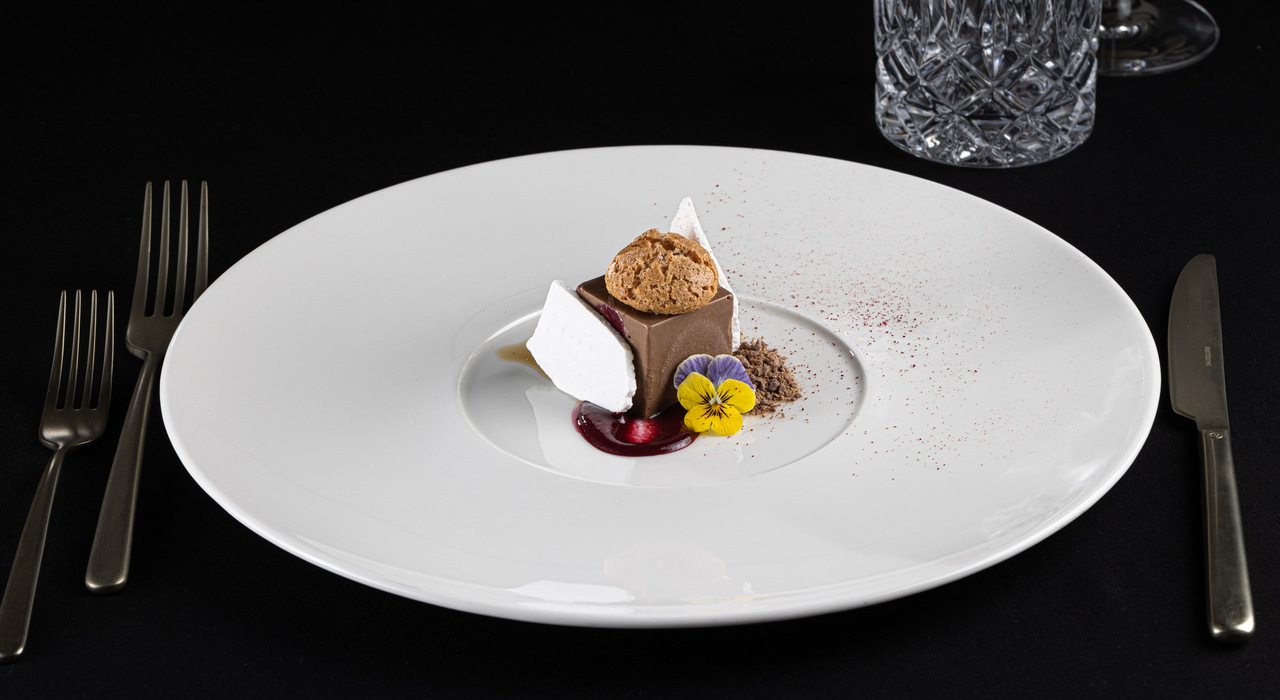 Mała porcja deseru z jadalnym kwiatem podana w stylu fine dining