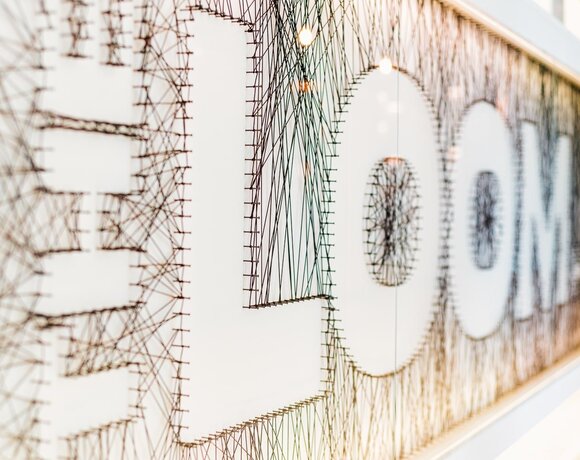 String-art wall spelling ROOM made from nails and black thread on a white panel, decorative hotel wall art