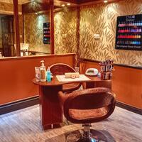 Manicure station with cushioned salon chair, wooden table with lotions and towel, wall display of colorful nail polishes.