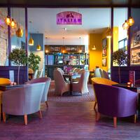 Cozy hotel Italian dining area with bar and gelato menu, soft pendant lighting, wicker chairs and indoor olive trees