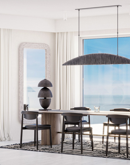 Jasna jadalnia w nadmorskim apartamencie z drewnianym stołem dla sześciu, wygodną sofą, rzeźbiarskimi lampami i panoramicznym widokiem na morze