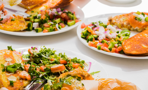 Brunchteller mit Räucherlachs, pochierten Eiern, Rucola-Tomatensalat und geröstetem Brot