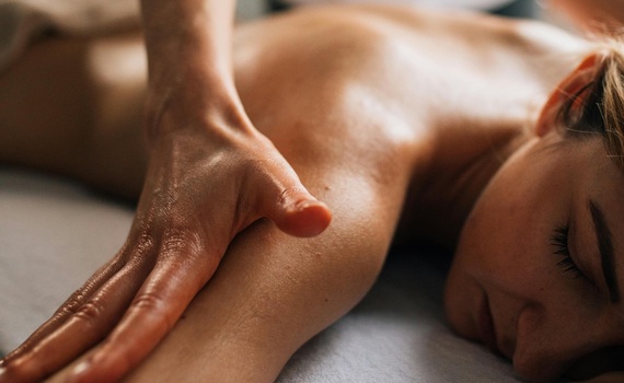 Relaksacyjny masaż w spa: gość leży na brzuchu, terapeuta wykonuje olejowe, długie ruchy na plecach i barku.