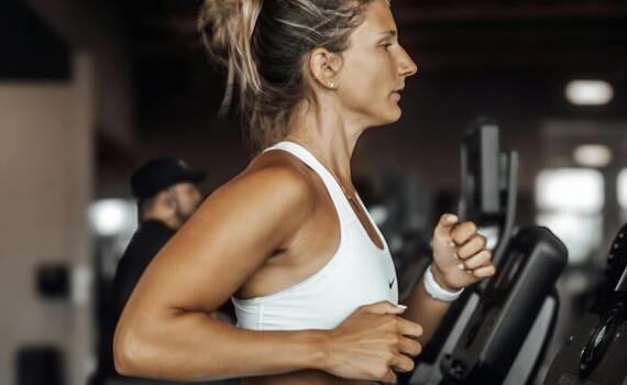 Gast joggt auf dem Laufband im modernen Hotel-Fitnessraum, sichtbare Cardiogeräte und lebhafte Trainingsatmosphäre