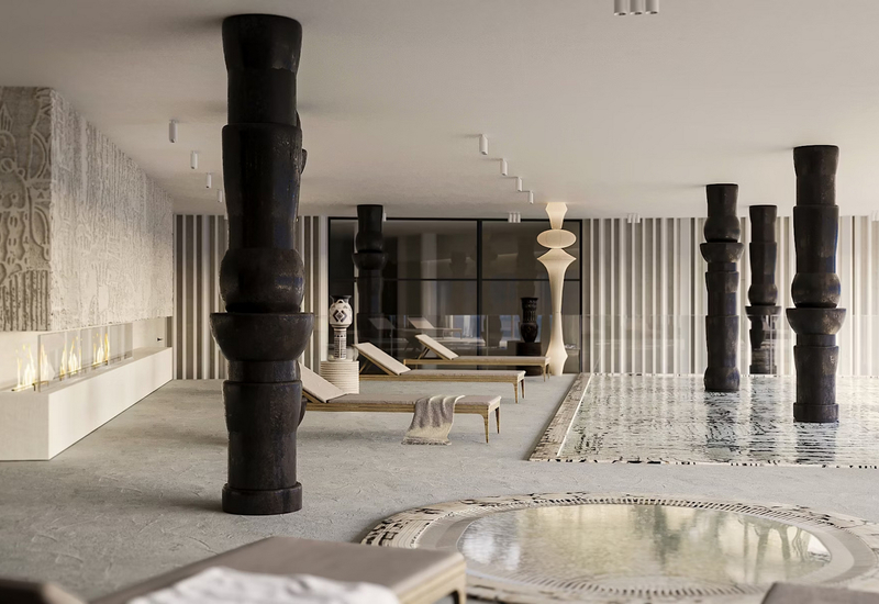 Spokojne spa wewnętrzne z płytkim basenem, ciemnymi rzeźbionymi kolumnami, leżakami, mniejszym mozaikowym basenem i liniowym kominkiem.