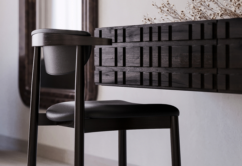 Ciemne drewniane krzesło przy wiszącej, fakturowanej konsoli z lustrem i suchymi kwiatami na minimalistycznej toaletce pokoju hotelowego.