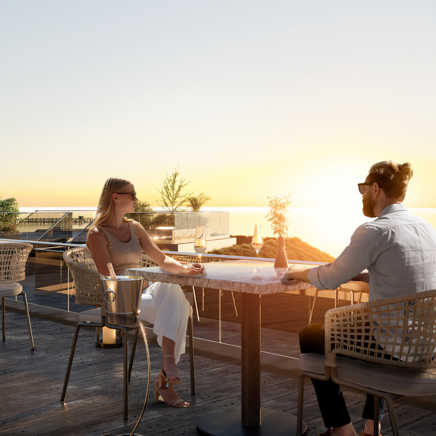 Para relaksuje się przy zachodzie słońca na tarasie dachowym hotelu nad morzem, marmurowy stolik, wiklinowe fotele i kieliszki