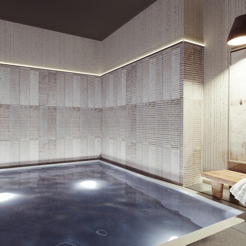 Wewnętrzny basen spa z podwodnym oświetleniem, fakturowane płytki, drewniana ławka z ręcznikiem i dyskretne światło.