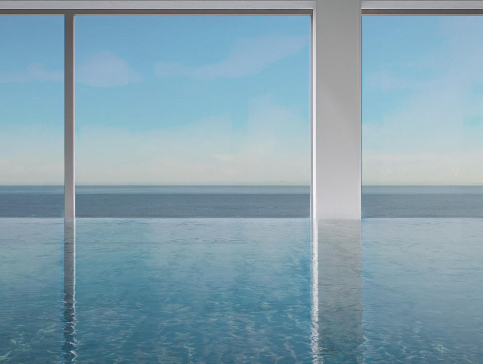 Wewnętrzny basen infinity z oknami sięgającymi podłogi i panoramicznym widokiem na spokojne morze i błękitne niebo