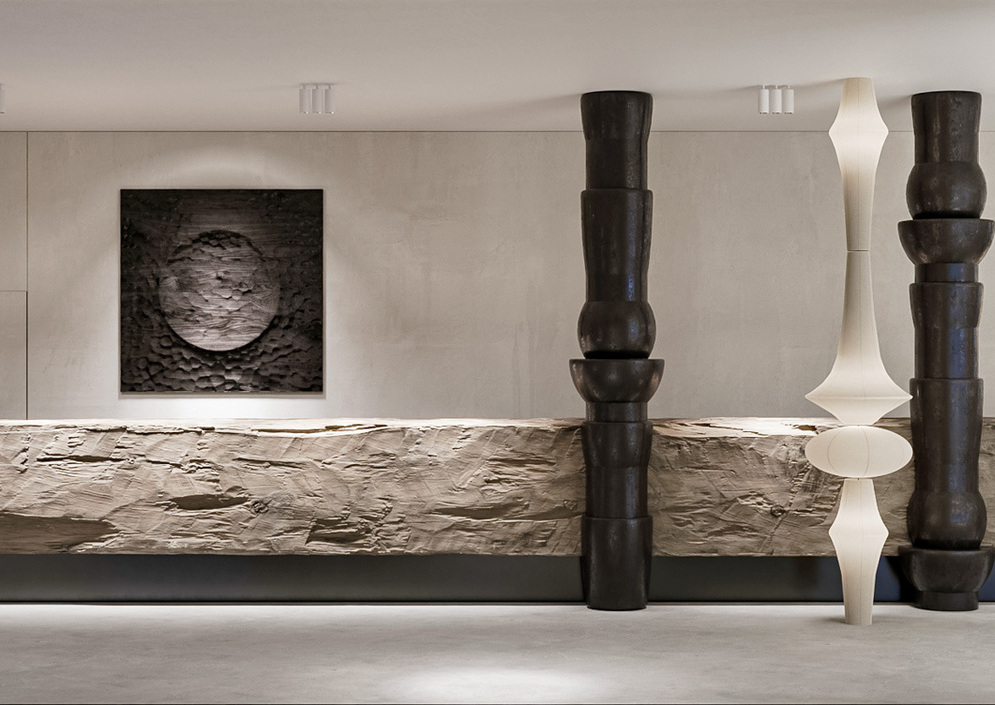 Minimalistyczna recepcja z fakturowanym kamiennym blatem, rzeźbiarskimi ciemnymi filarami i miękkim oświetleniem.