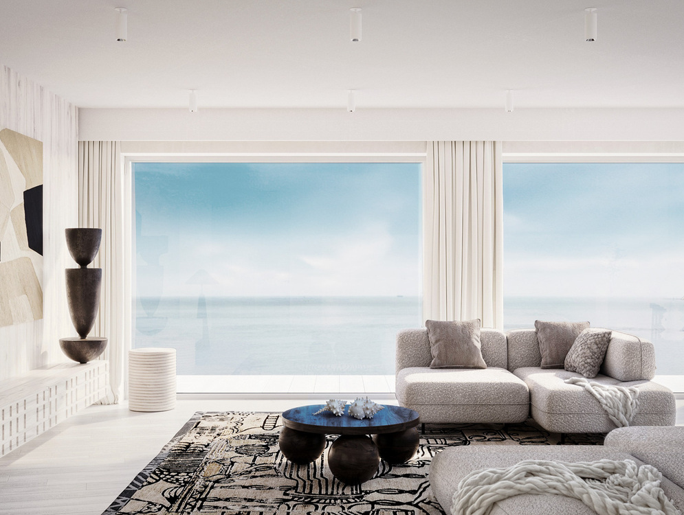 Przestronny salon przy plaży z oknami od podłogi do sufitu, miękką sofą modułową, wzorzystym dywanem, rzeźbiarską dekoracją i rozległym widokiem na morze.