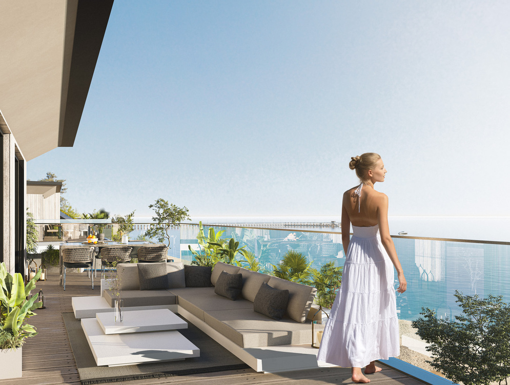 Przestronny taras z widokiem na morze, narożną sofą, stołem jadalnym, bujnymi roślinami i szklaną balustradą; kobieta w białej sukience patrzy na morze.