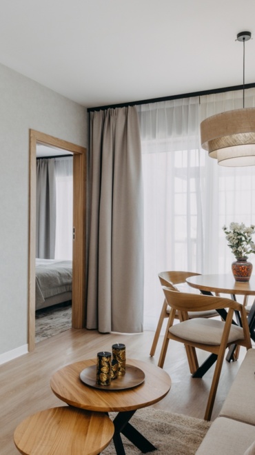 Widok na pokój hotelowy z kanapą, stolikiem kawowym, stołem, krzesłami i telewizorem