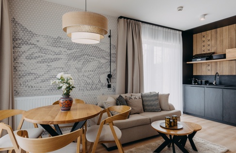 Pokój hotelowy z kanapą, stołem i krzesłami oraz niewielką strefą kuchenną