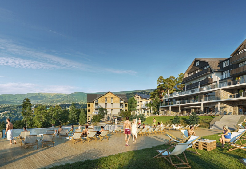 Leżaki stojące nad brzegiem basenu zewnętrznego, hotel oraz góry w tle