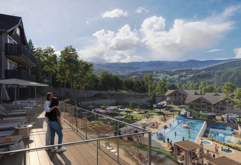 Para patrzy z tarasu na hotelowy aquapark, góry w tle
