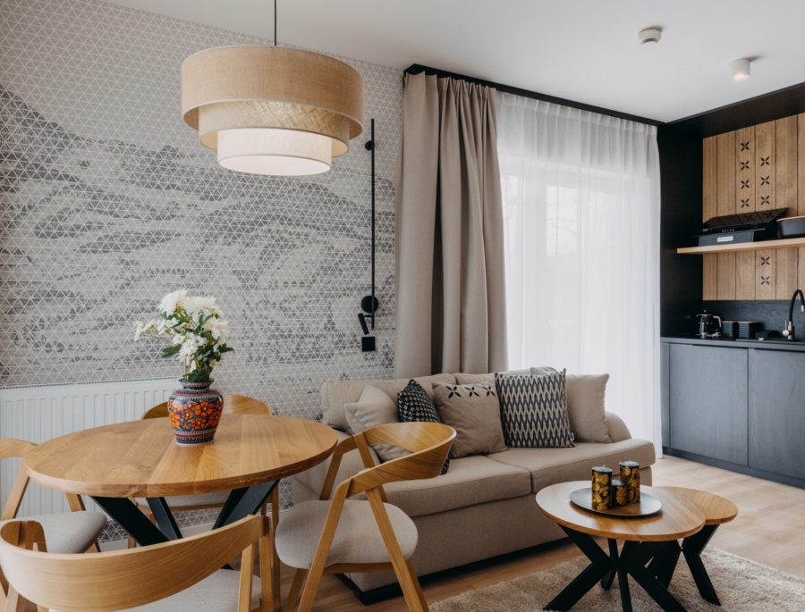 Pokój hotelowy z kanapą, stołem i krzesłami oraz niewielką strefą kuchenną