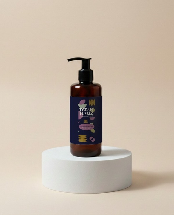 Bursztynowa butelka z pompką z hotelowym żelem do rąk i ciała na białym podium, nowoczesna etykieta z kolorowymi abstrakcyjnymi wzorami