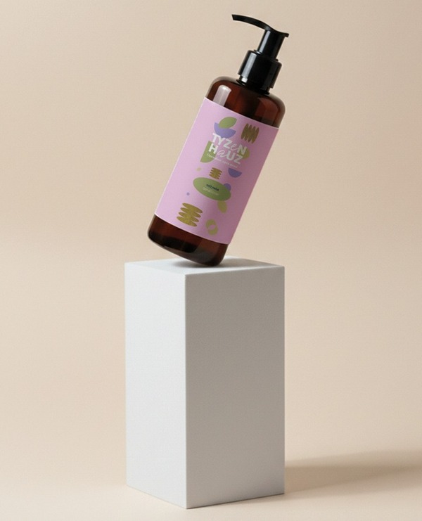 Bursztynowa butelka z dozownikiem z hotelowym płynem do rąk, różowa etykieta z motywem roślinnym na białym piedestale