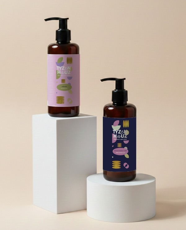 Bursztynowe butelki z pompkami i pastelowymi etykietami na białych podestach, hotelowe balsamy do rąk i ciała