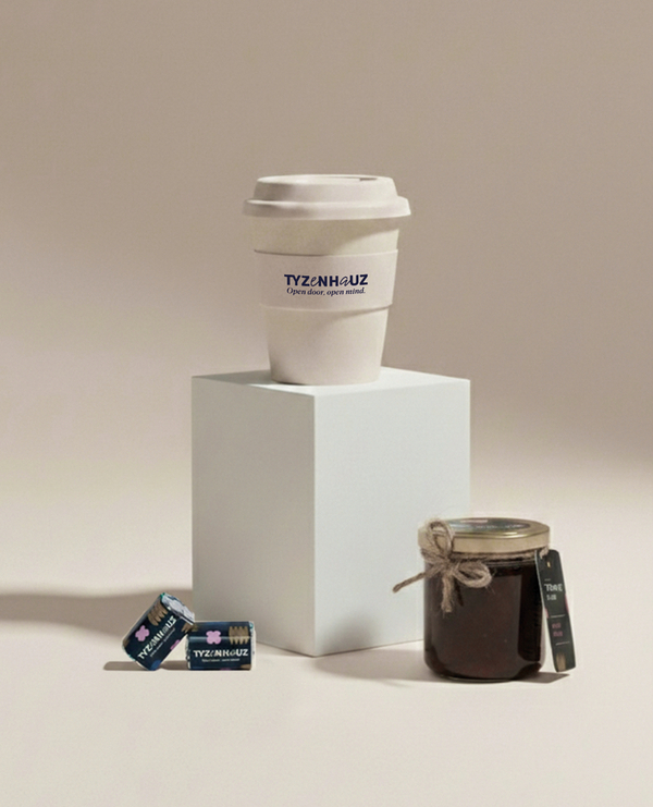 Kubek na wynos TYZENHAUZ na podstawce, obok domowy słoik dżemu i dwie zapakowane kostki cukru