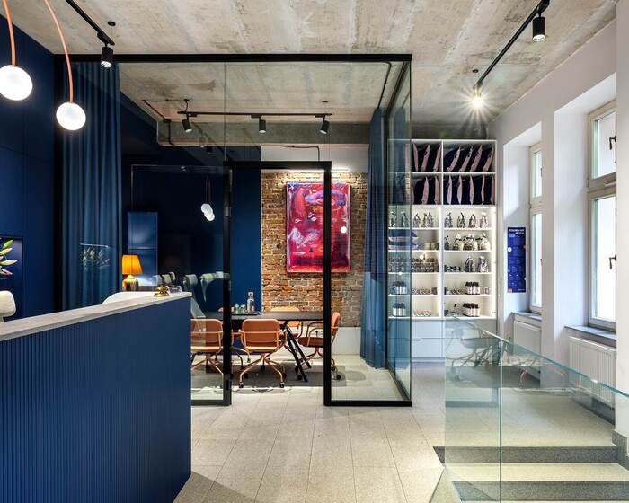 Nowoczesna recepcja hotelowa z granatowymi ścianami, szklaną salą konferencyjną i półkami z produktami hotelowymi.