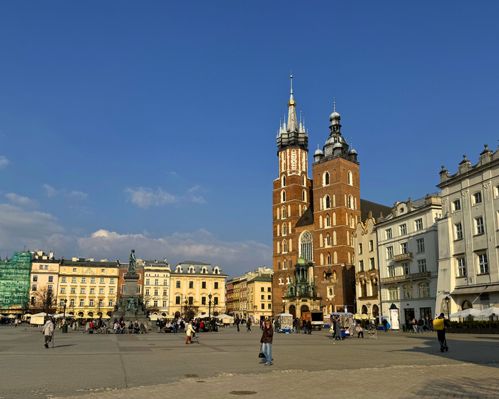 Przestronny rynek z ceglanym, gotyckim kościołem o dwóch wieżach, zabytkowymi kamienicami i kawiarnianymi ogródkami pod błękitnym niebem