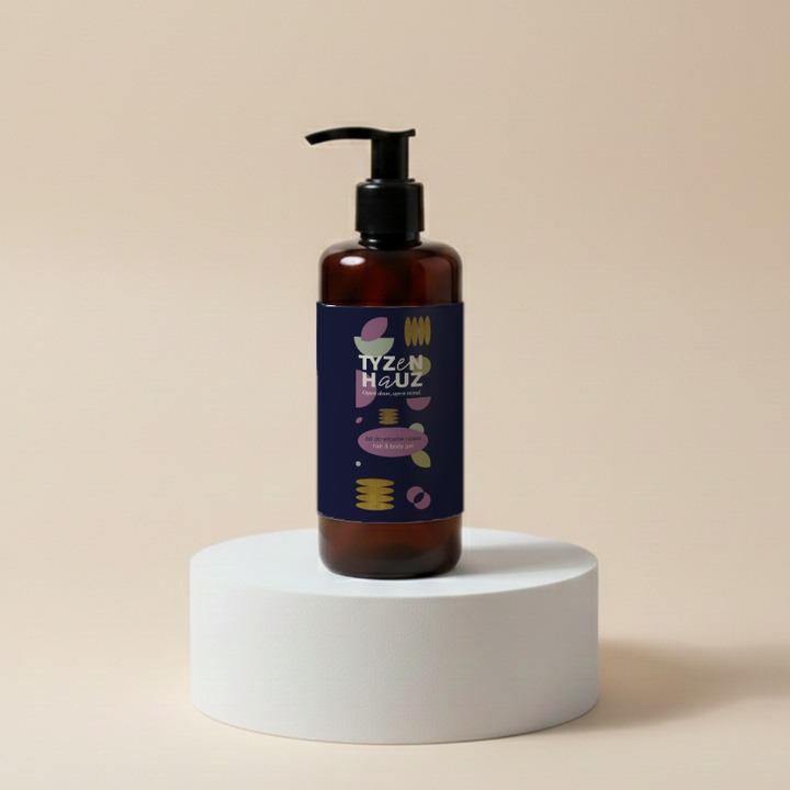 Bursztynowa butelka z pompką z hotelowym żelem do rąk i ciała na białym podium, nowoczesna etykieta z kolorowymi abstrakcyjnymi wzorami