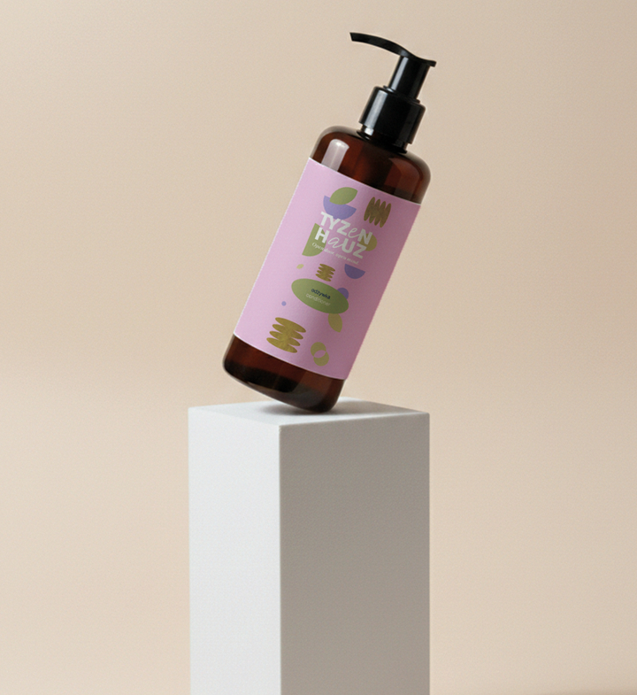 Bursztynowa butelka z dozownikiem z hotelowym płynem do rąk, różowa etykieta z motywem roślinnym na białym piedestale