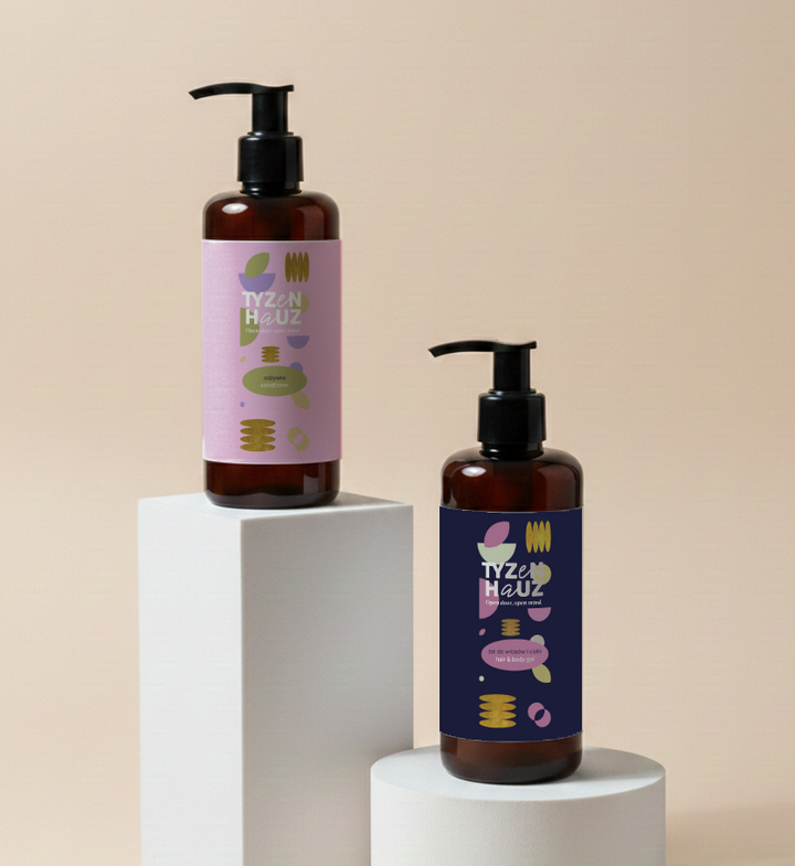 Bursztynowe butelki z dozownikiem z hotelowymi kosmetykami na białych podestach, kolorowe etykiety, minimalistyczny zestaw łazienkowy.